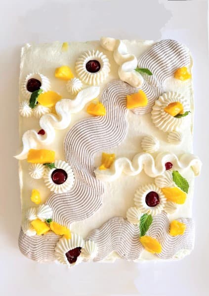 Mango cream sheet cake with decorative piping and fresh mango